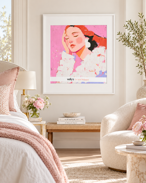 A framed art print featuring a stylized portrait of a woman with red hair and white ruffled clothing on a pink background, displayed on a light beige wall in a modern, sunlit bedroom setting.