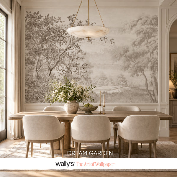 A large-scale wall mural featuring a monochrome garden landscape with trees and a river, styled in a dining room setting with a wooden dining table, six upholstered chairs, and a hanging light fixture. A white banner at the bottom displays the text 'DREAM GARDEN' and 'wallys The Art of Wallpaper'.