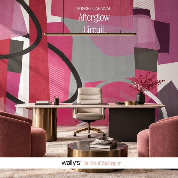 An abstract wallpaper mural in a modern office setting, featuring bold geometric shapes in pink, magenta, gray, black, and white. The room includes a light-colored desk, a cream office chair, two pink armchairs, and a gold pendant light.