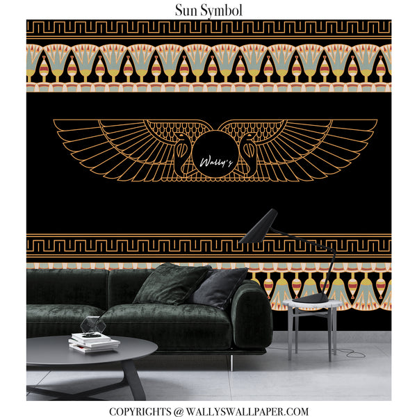 A black wallpaper design featuring a central gold Egyptian winged sun symbol with the script 'Wally's' inside, flanked by decorative gold and beige geometric borders. The wallpaper is shown in a modern living room setting behind a dark green velvet sofa and a black side table with a lamp.