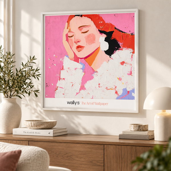 A framed art print featuring a stylized portrait of a woman with closed eyes on a pink background, displayed on a wall above a wooden console table in a modern living room setting. The print includes the text 'wallys The Art of Wallpaper'.
