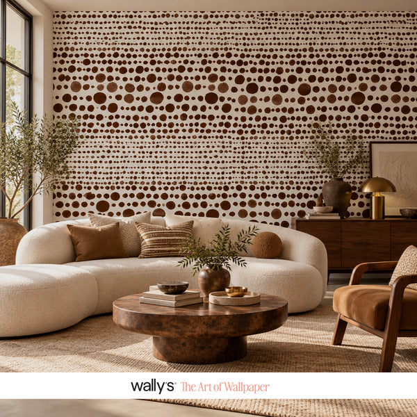 A styled living room featuring a large wall mural with a brown and white dotted pattern, styled with a cream-colored sectional sofa, a round wooden coffee table, and a brown armchair.